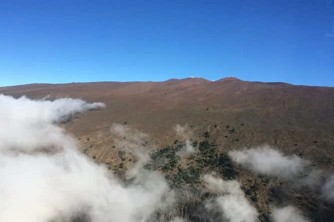 Clouds drifting below a bare brown volcanic slope