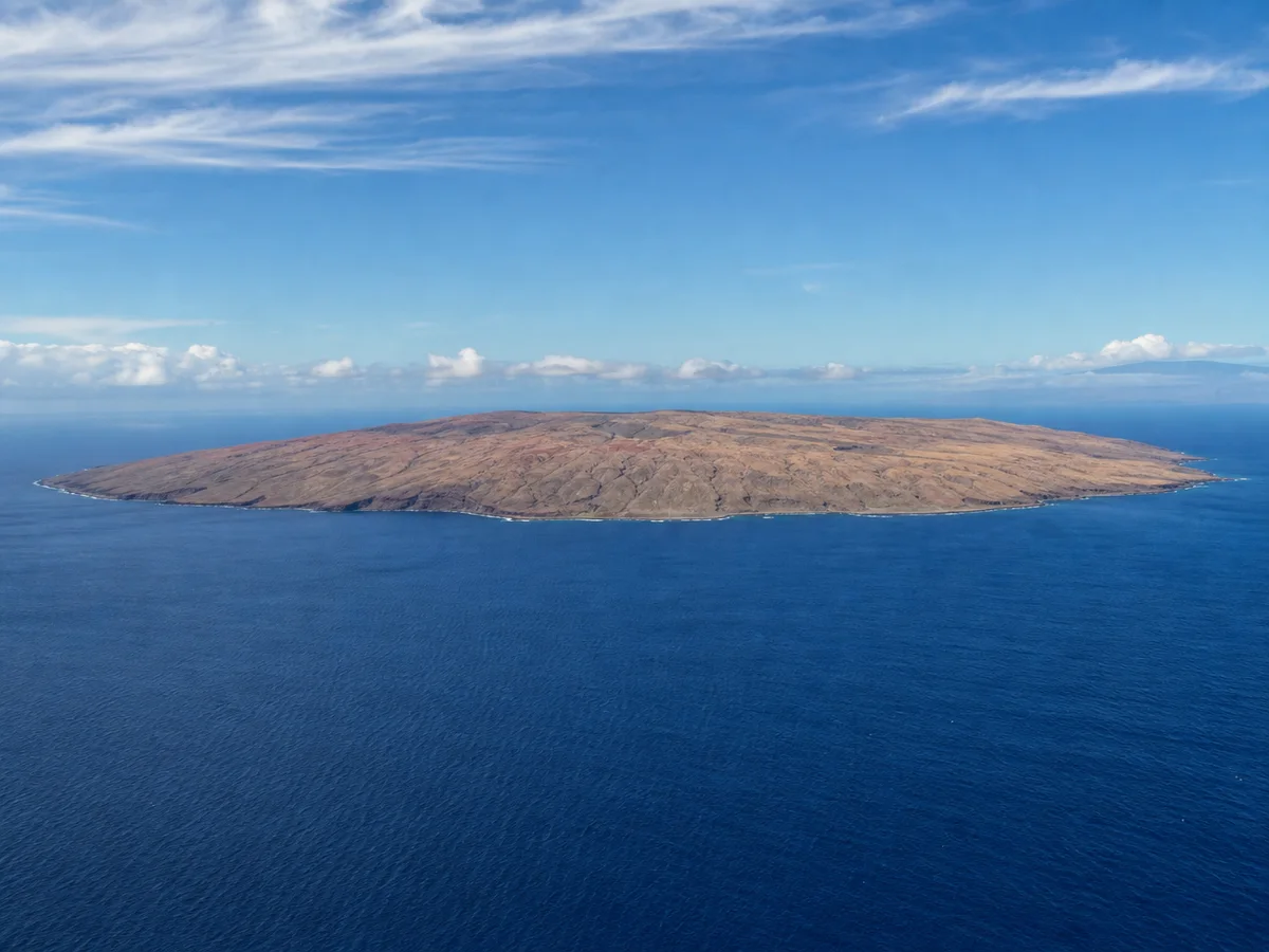 A low brown island on a calm deep blue sea